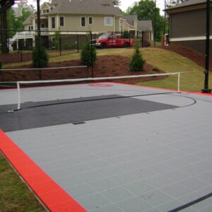 Outdoor residential multipurpose court with a tennis net and basketball hoop.