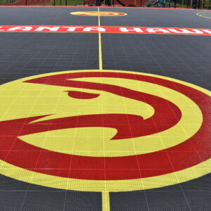 Outdoor basketball court constructed with Atlanta Hawks logo in the middle.