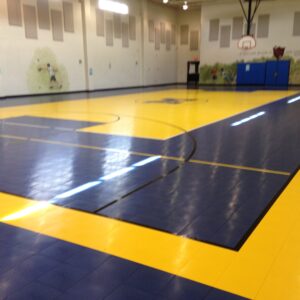 School gymnasium court with blue and yellow gym flooring and school logo.