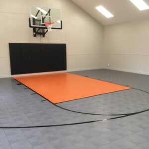 Indoor basketball court with gray and orange indoor sport flooring tiles.
