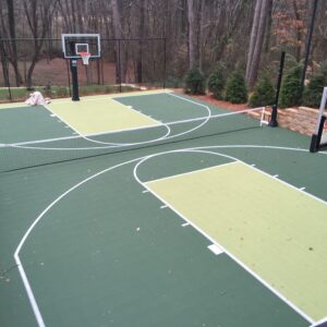 Outdoor residential multipurpose court with baseball hoops and volleyball net in a wooded residential area.