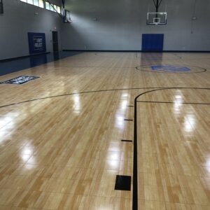 Indoor basketball court flooring with a Legacy Project logo.