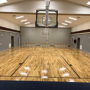 School auditorium with gymnasium flooring and basketball court.