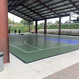 Outdoor basketball court with a pavillion roofing overtop.