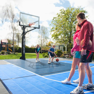 Family playing on new home outdoor basketball court installation.
