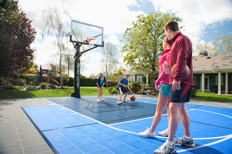 Family playing on new home outdoor basketball court installation.