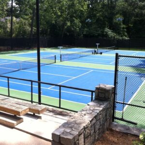 Outdoor tennis court with players holding tennis rackets.