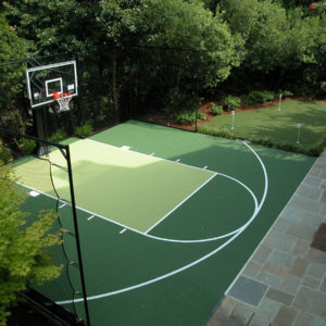 backyard basketball court next to putting greens with golf holes