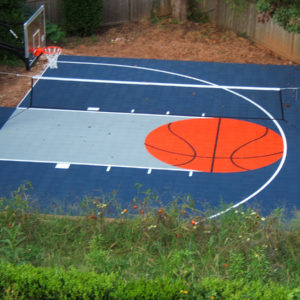blue backyard basketball court with volleyball net and orange basketball logo
