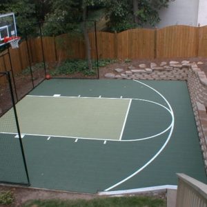 half court backyard basketball court with half fence and stone walkway